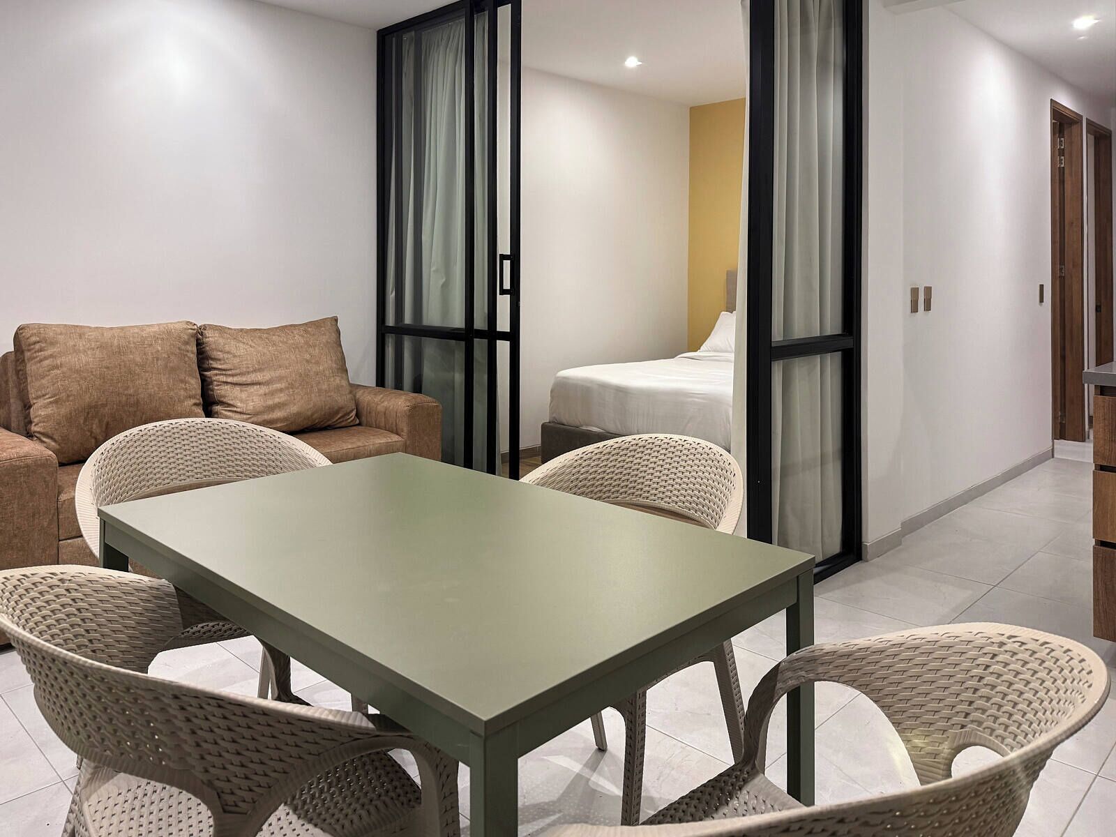 Een moderne hotelkamer met een bank, een eettafel en rieten stoelen.
