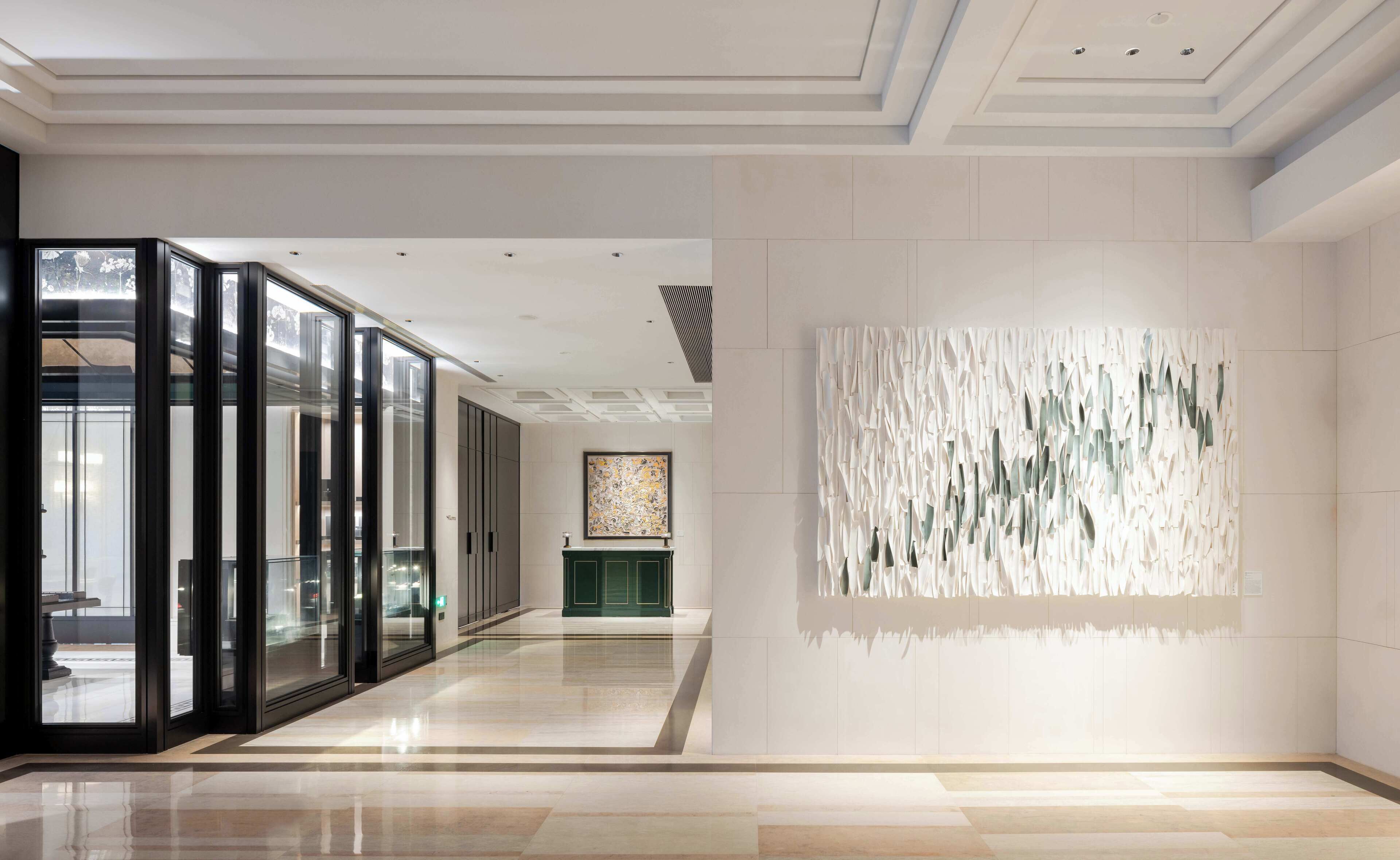 Um interior moderno com divisória de vidro, balcão de recepção verde e uma obra de arte com textura na parede.