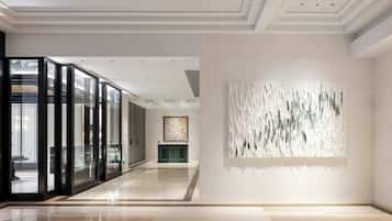 Um interior moderno com divisória de vidro, balcão de recepção verde e uma obra de arte com textura na parede.