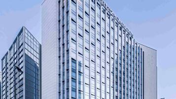 Un hotel moderno con una estructura alta y rectangular y fachada de vidrio.