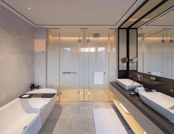 Un baño moderno con ducha de vidrio, dos lavamanos y un espejo grande.