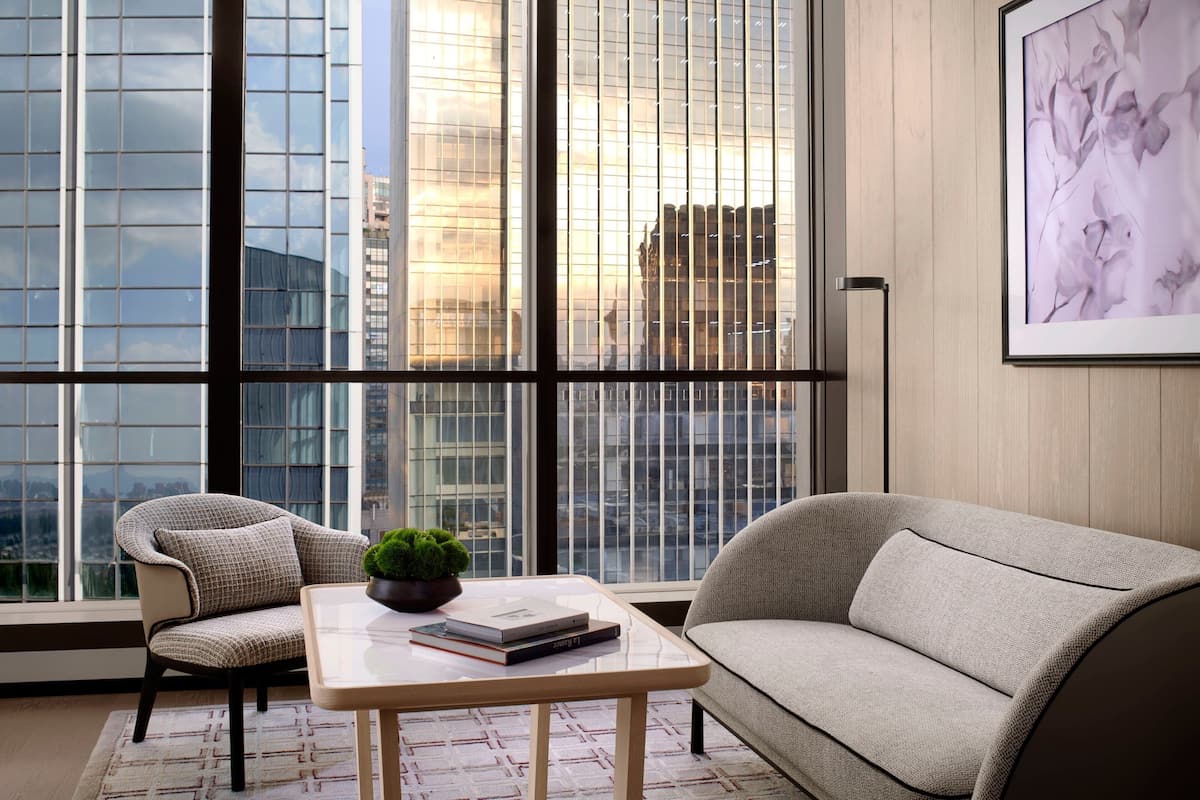 A modern living room with a sofa, armchair, and a coffee table with books and a plant.