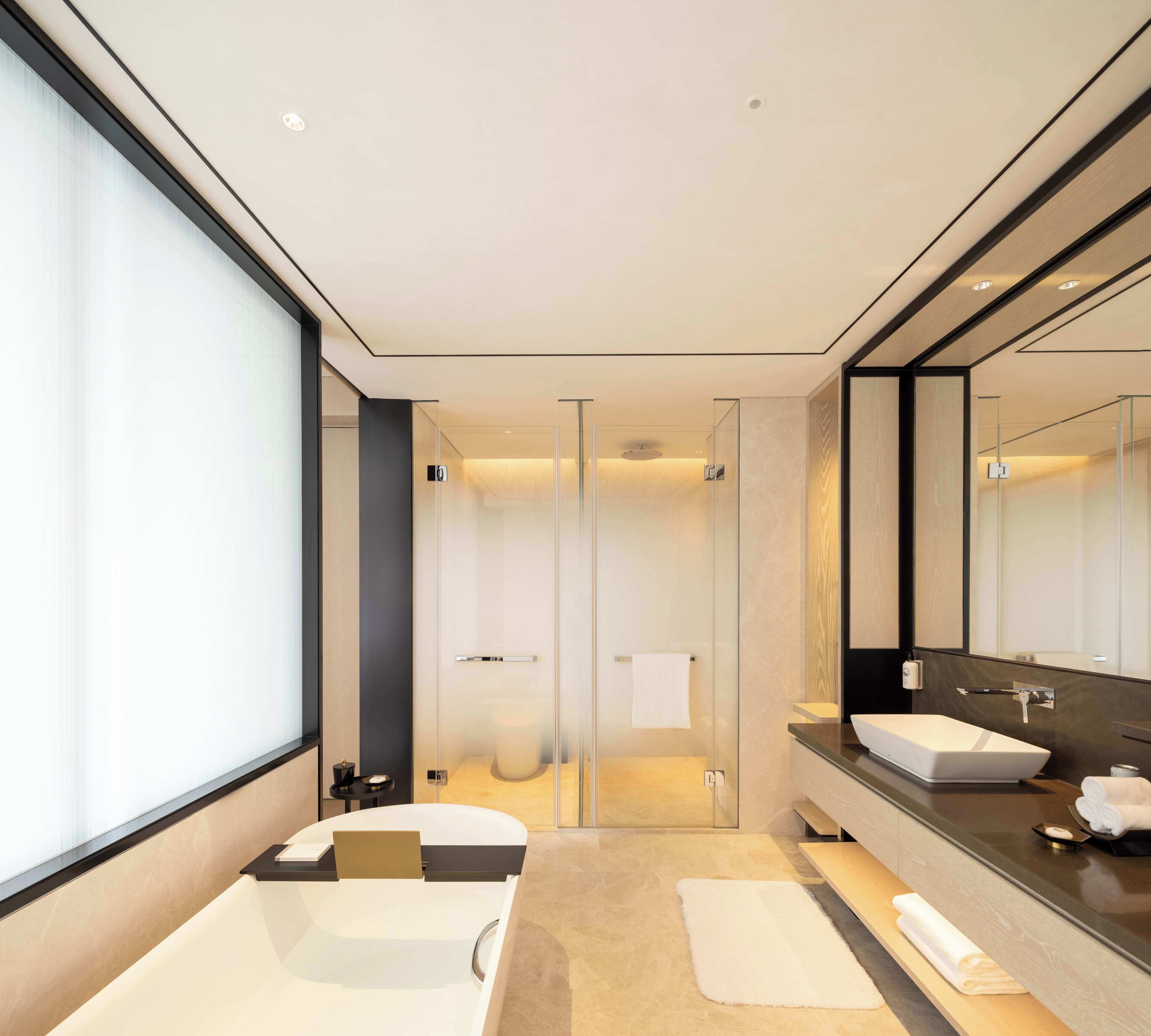 A modern bathroom with two sinks, a large mirror, and a glass shower enclosure.