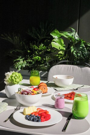 A table with breakfast items including fruits, a bowl of salad, and drinks.