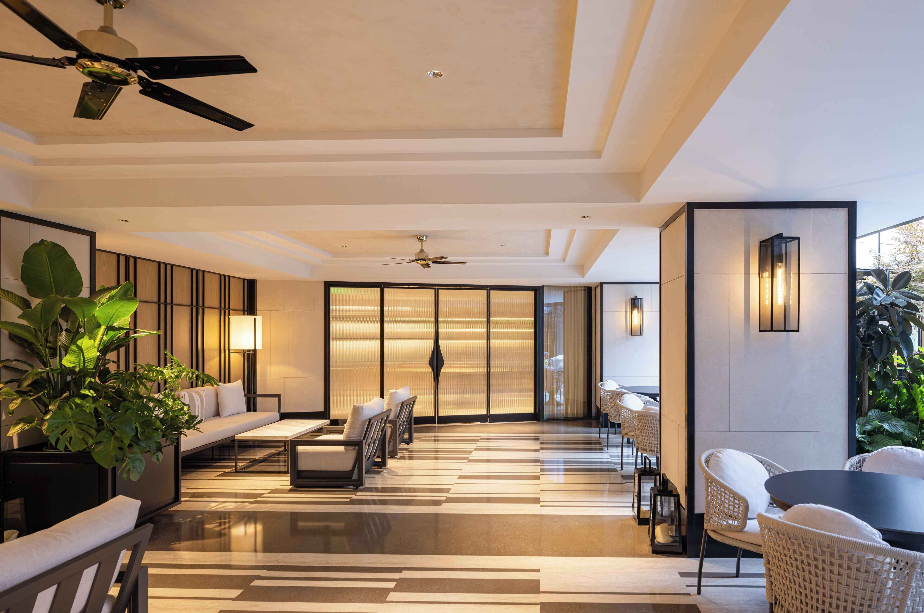 A modern hotel lobby with a sofa, chairs, a coffee table, and a ceiling fan.