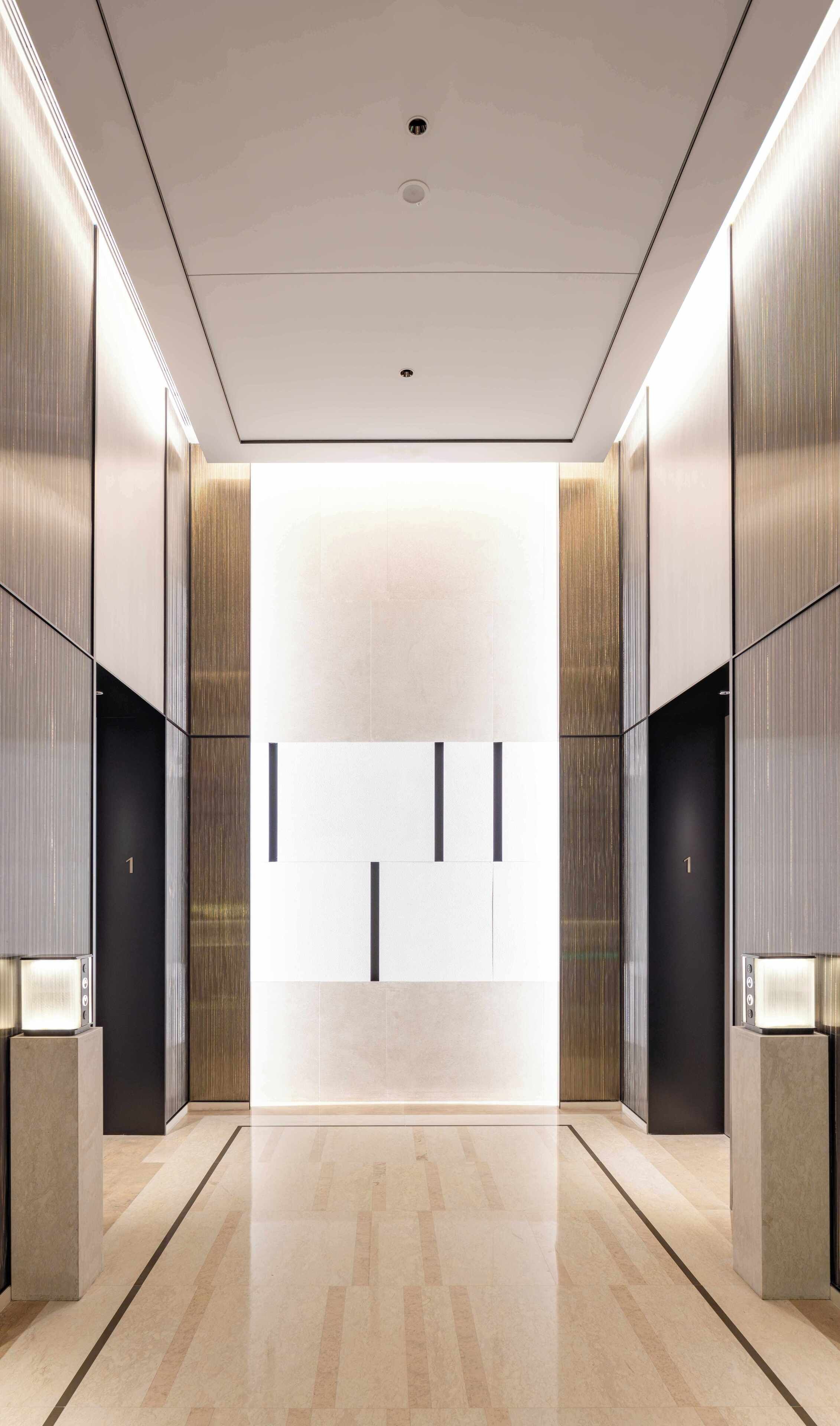 A modern elevator interior with metallic walls and a reflective floor.