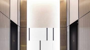 A modern elevator interior with metallic walls and a reflective floor.