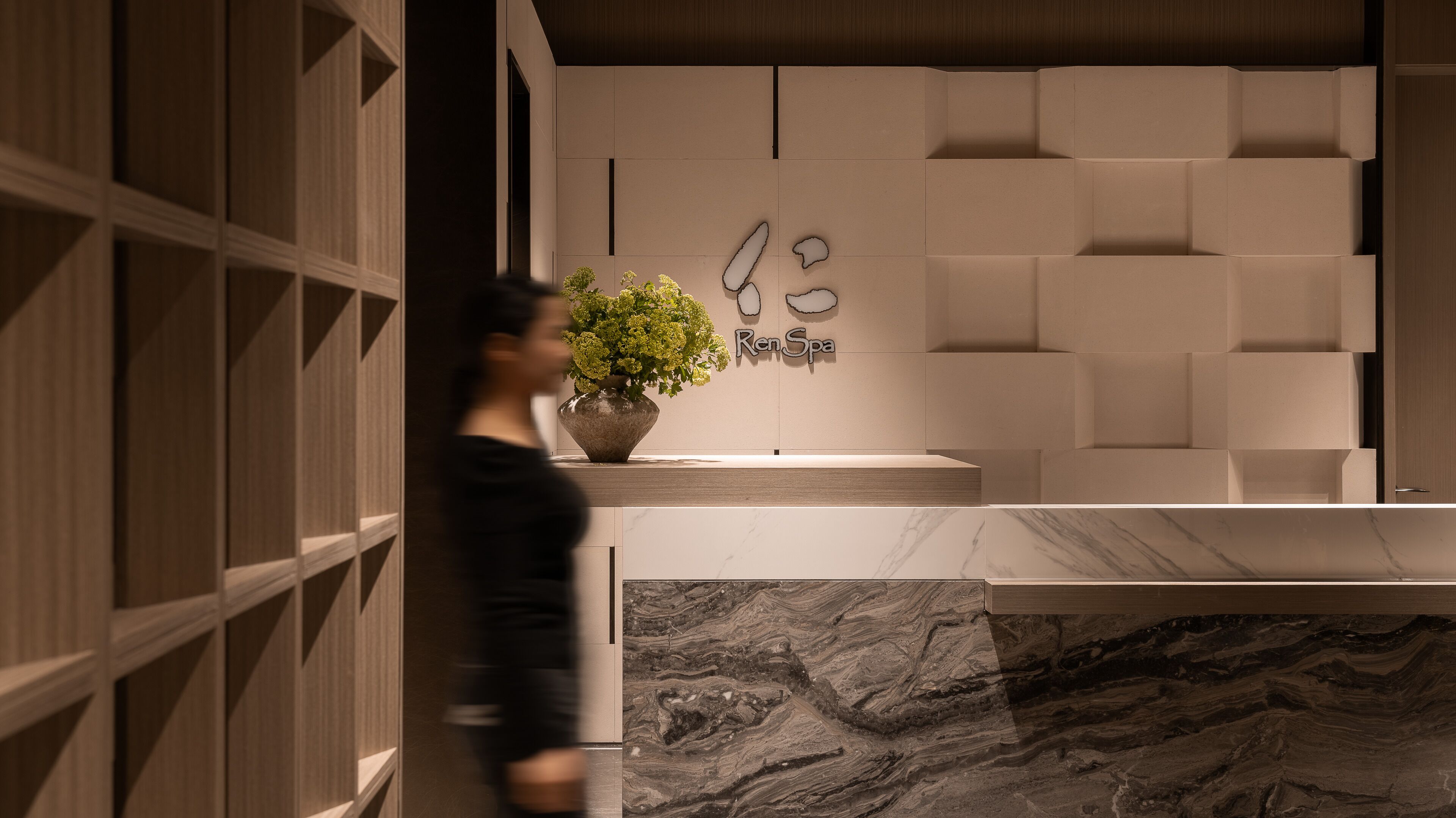 A reception area with a marble counter, a potted plant, and a wall-mounted sign reading "RenSpa".