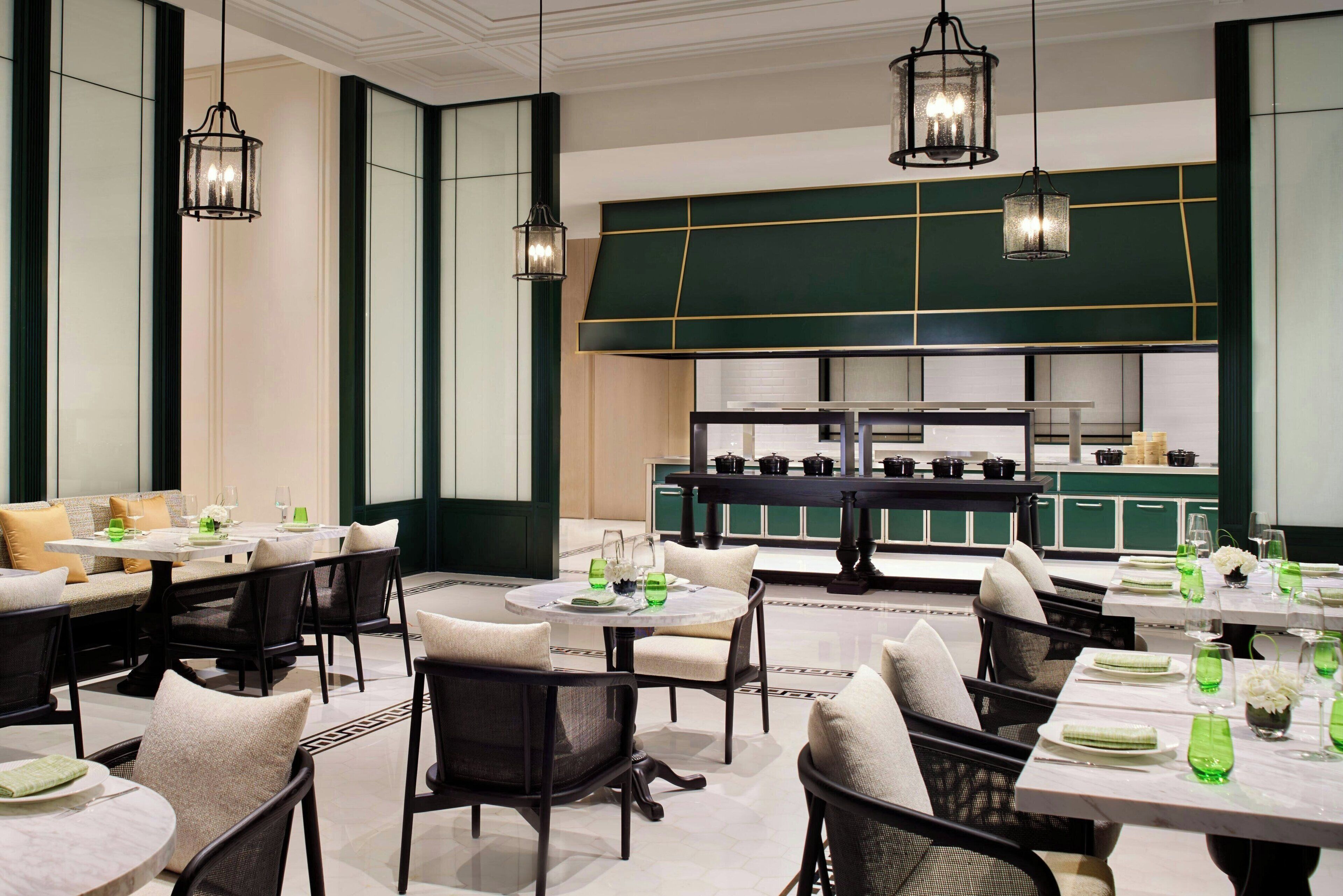 Un restaurante con mesas redondas, sillas negras y detalles en verde.