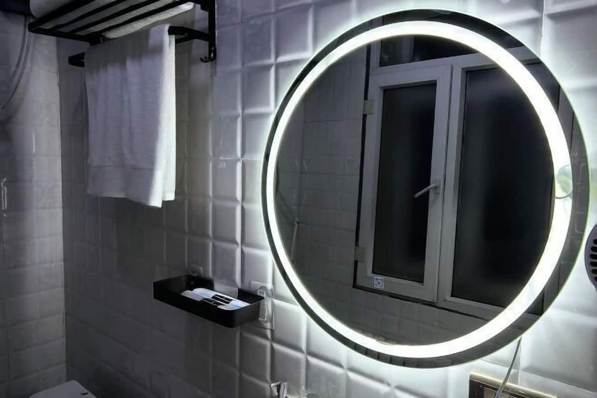 Une salle de bain avec un miroir rond, un porte-serviettes et une étagère contenant des articles de toilette.