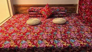 Una cama con colcha estampada, dos cestas tejidas y una pila de almohadas.