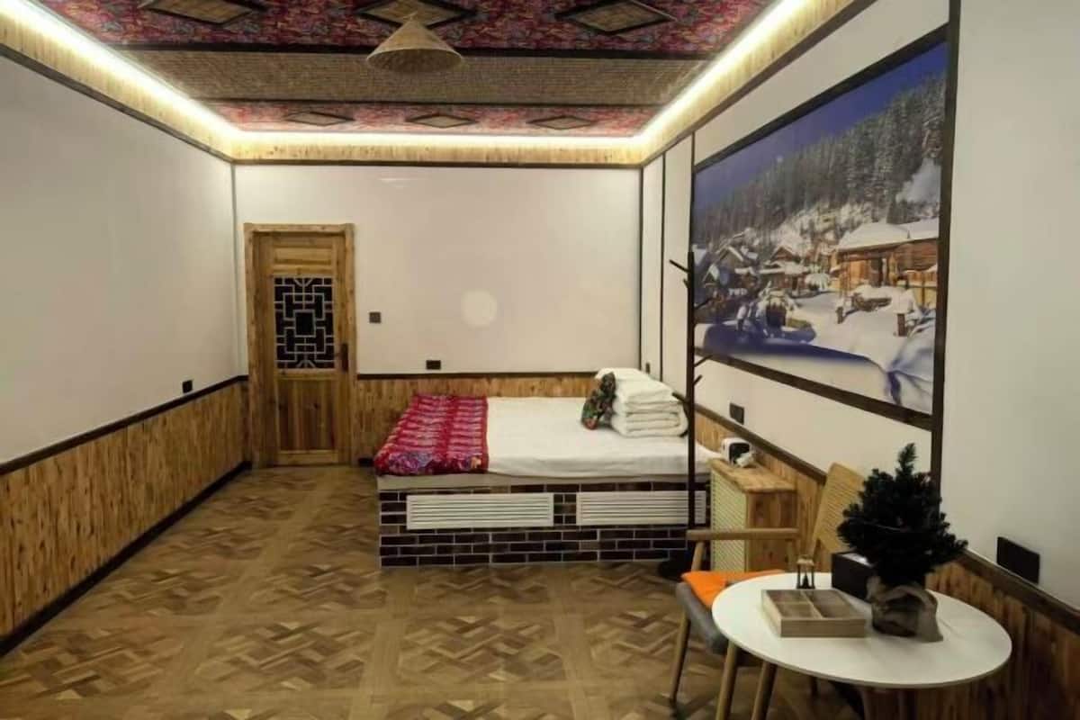 Une pièce comprenant un lit, une petite table, une chaise, un mur décoratif et une porte.