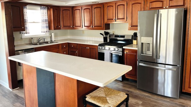 Una cocina con armarios de madera, un refrigerador de acero inoxidable, una estufa y un lavamanos.