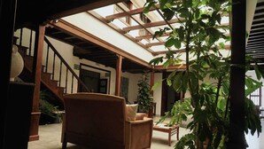 A spacious indoor area with a wooden staircase, a large potted plant, and a comfortable seating area. - La Casona de Arona (Arona)