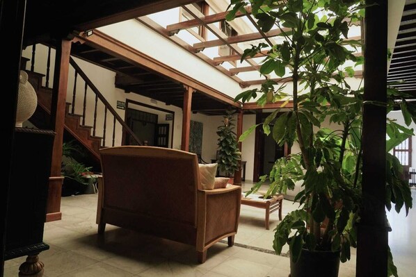 A spacious indoor area with a wooden staircase, a large potted plant, and a comfortable seating area. - La Casona de Arona (Arona)