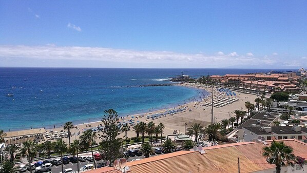 A coastal town with a beach, clear blue sea, and buildings with red-tiled roofs. - La Casona de Arona (Arona)