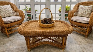 A wicker table with a basket of pinecones, flanked by two wicker chairs with patterned cushions, set on a tiled floor. - La Casona de Arona (Arona)