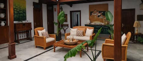A spacious living area with a sofa set, a coffee table, and potted plants.