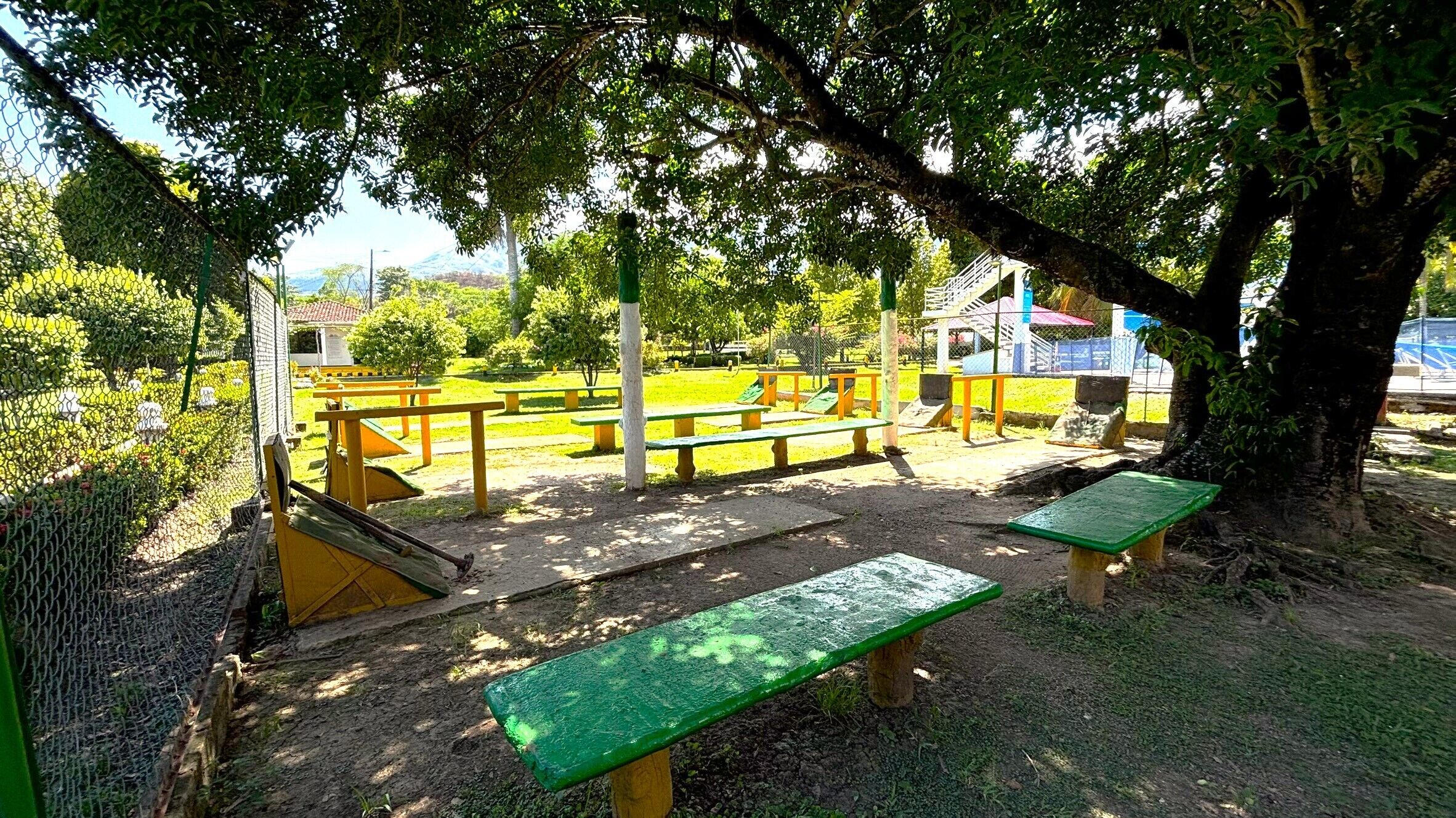 Un parque con mesas de picnic, un área de juegos y una zona vallada.