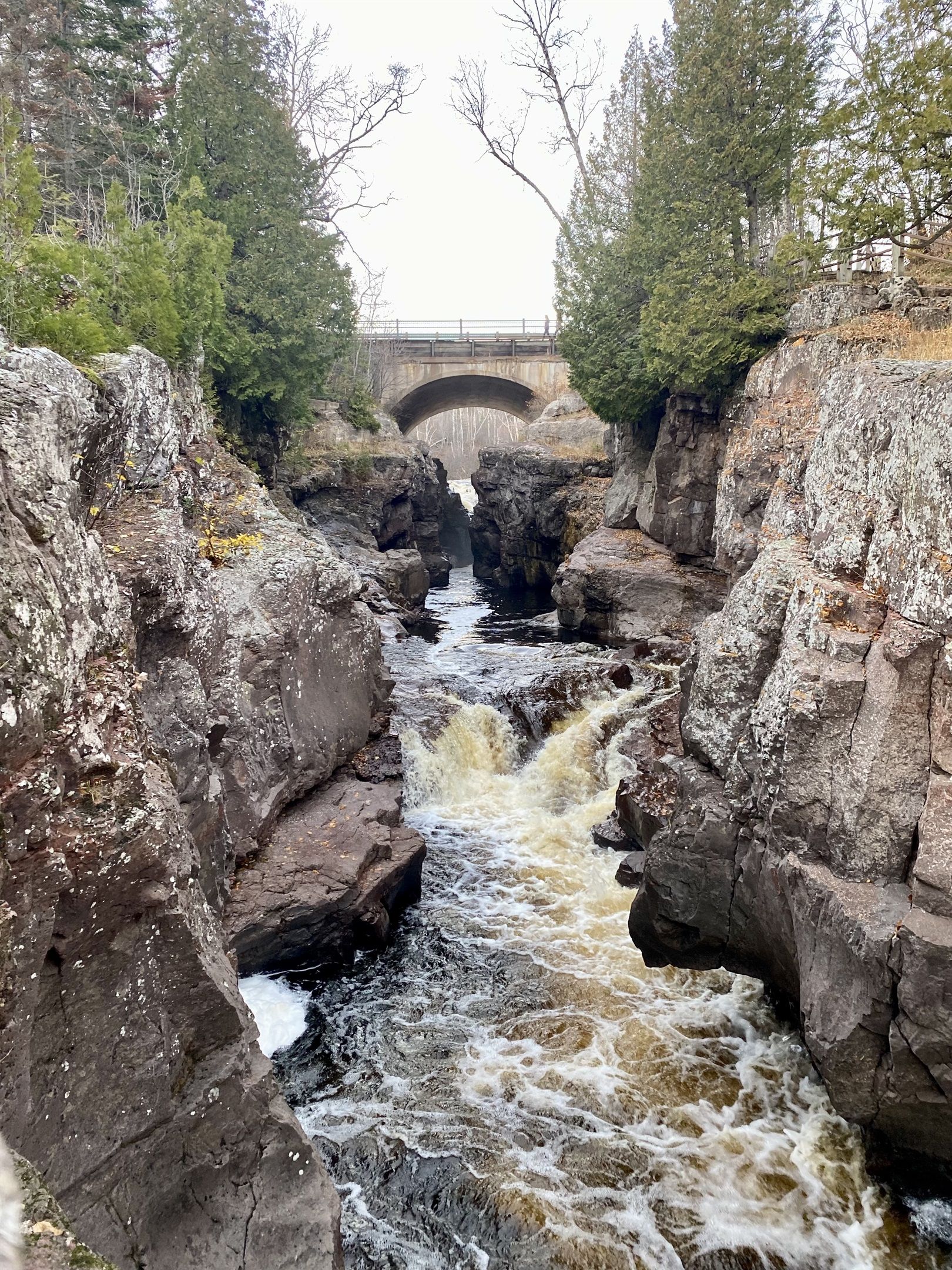A rocky river with a bridge in the background.