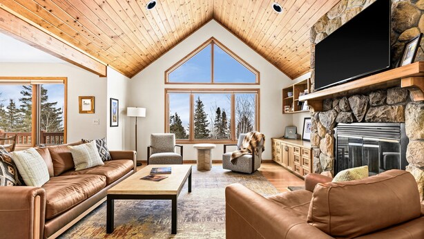 A spacious living room with a high ceiling, large windows, a stone fireplace, and leather furniture. - Perfect Location|Game Garage|King Beds|Views (Tofte)