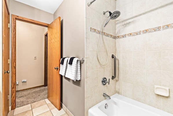 A bathroom with a shower, a bathtub, and a towel rack with towels.