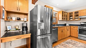 A modern kitchen with wooden cabinets, stainless steel appliances, and a coffee maker on the counter. - Perfect Location|Game Garage|King Beds|Views (Tofte)