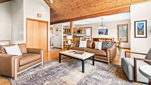 A spacious living area with a high wooden ceiling, leather sofas, a coffee table, and a view of the kitchen and dining area. - Perfect Location|Game Garage|King Beds|Views (Tofte)