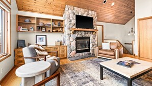 A cozy living room with a stone fireplace, wooden ceiling, and a comfortable seating area. - Perfect Location|Game Garage|King Beds|Views (Tofte)