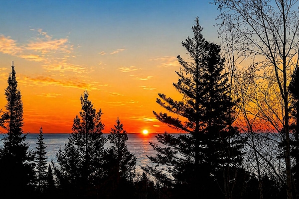 Wake up slowly at Treetops and step out onto the deck with a warm cup of coffee in your hand as the sun begins to rise over Lake Superior. The first light peeks through the trees, glowing softly between the branches before spilling out across the water.