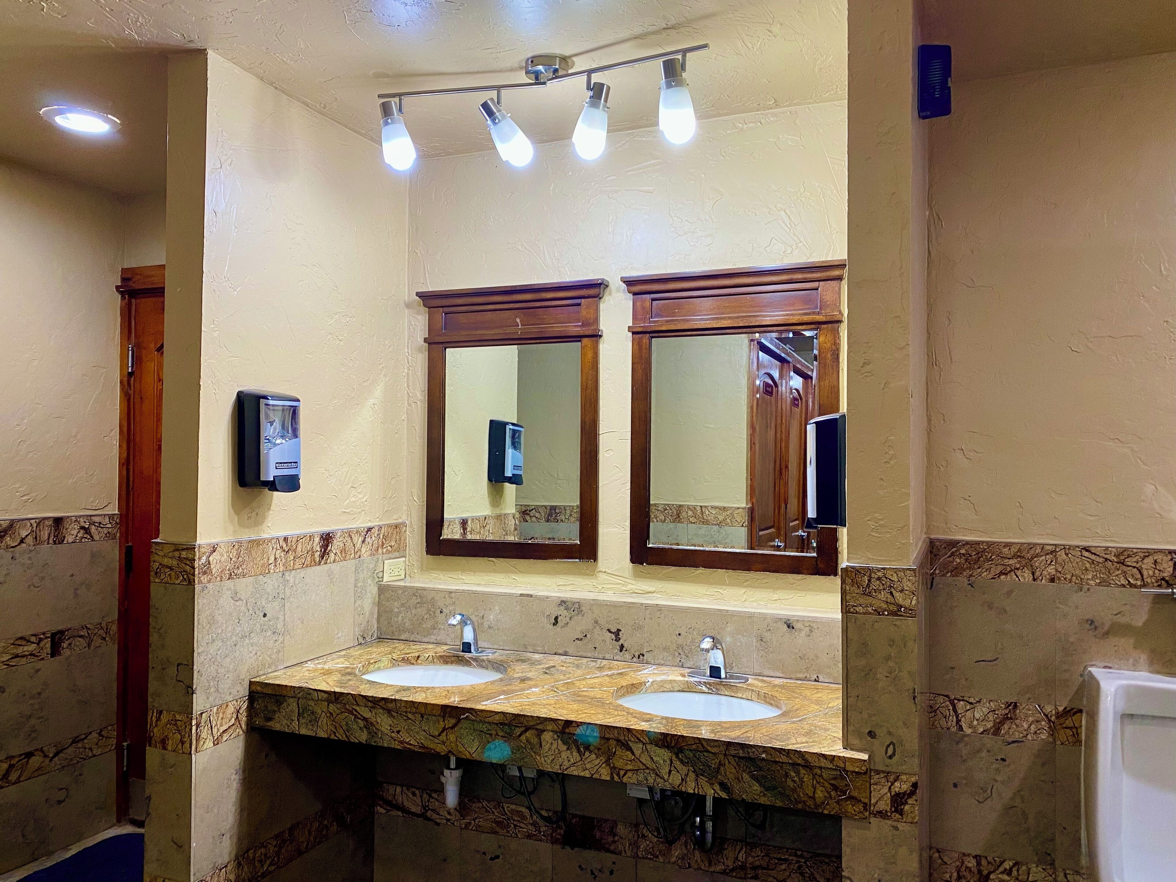 A bathroom with two sinks, a mirror, and a hand dryer.