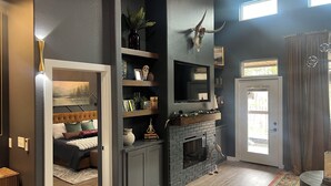 A modern living room with a fireplace, built-in shelves, and a cozy seating area. - Cozy cabin in lovely Longview with WiFi, AC (Longview)