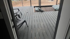 A wooden deck with a ceiling fan, a view of a wooded area, and a hammock. - Cozy cabin in lovely Longview with WiFi, AC (Longview)