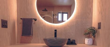 Une salle de bain en bois avec un miroir rond, un lavabo et un porte-serviettes.