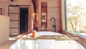 A modern kitchen with wooden cabinetry, a white countertop, and a window with a view of trees. - Breathtaking Designer A-Frame In The High Desert (Mountain Center)