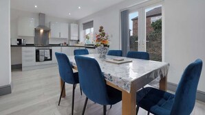 A modern kitchen with white cabinets, a central island, and a dining area with blue chairs and a table.