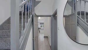 A hallway with a staircase, a door, and a mirror.