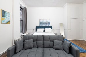 Un dormitorio moderno con una cama grande, un sofá gris y obras de arte en las paredes.