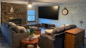 Ein Wohnzimmer mit Kamin aus Stein, einem großen Flachbildfernseher und einer gemütlichen Sitzecke.