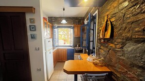 A compact kitchen with a stone wall, a wooden table, and a view to the outside.