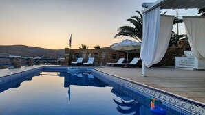 A pool area with lounge chairs and a view of the landscape.
