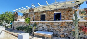 A stone building with a white pergola, two doors, and a cactus plant. - Cycladic House with a Pool. Exceptional views and 2min walk from the beach. (Kythnos)