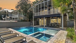 Ein zweistöckiges Haus mit Swimmingpool, Sitzgelegenheiten im Freien und einer überdachten Terrasse.