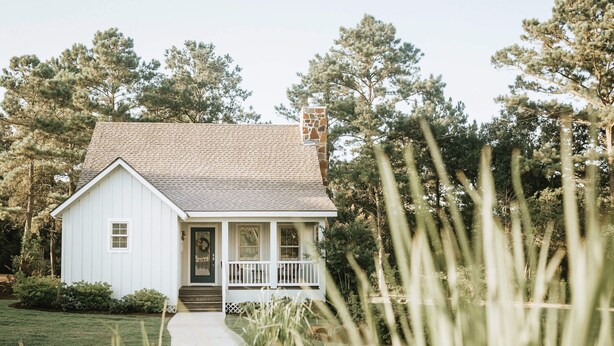 A white house with a front porch, a chimney, and a pathway leading to the entrance. - The Vine - Elegant "Wild Rose" Cottage on Vineyard with Private Lake, Sleeps 4 (New Ulm)