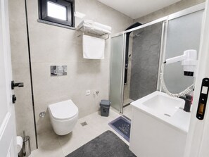 Een moderne badkamer met toilet, douche en wastafel.