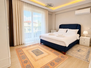 A hotel room with a bed, bedside tables, an air conditioning unit, and a view of the outdoors. - Zümrüt villaları  (Sapanca)