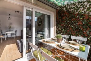 A dining area with a table set for two, a sliding glass door leading to an outdoor space, and a wall covered with climbing plants.