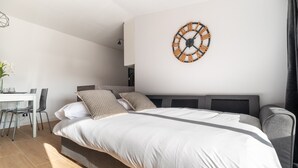Un dormitorio moderno con una cama grande, un escritorio y un reloj de pared.