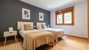Ein Schlafzimmer mit zwei Betten, einem Nachttisch, einem Fenster mit Aussicht und Bildern an der Wand.