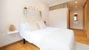 Ein Schlafzimmer mit einem großen Bett, einer Nachttischschublade mit Dekoration und Blick auf den Flur.